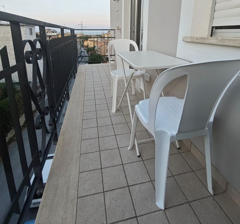 Balcone con sedie e vista sui tetti verso il mare