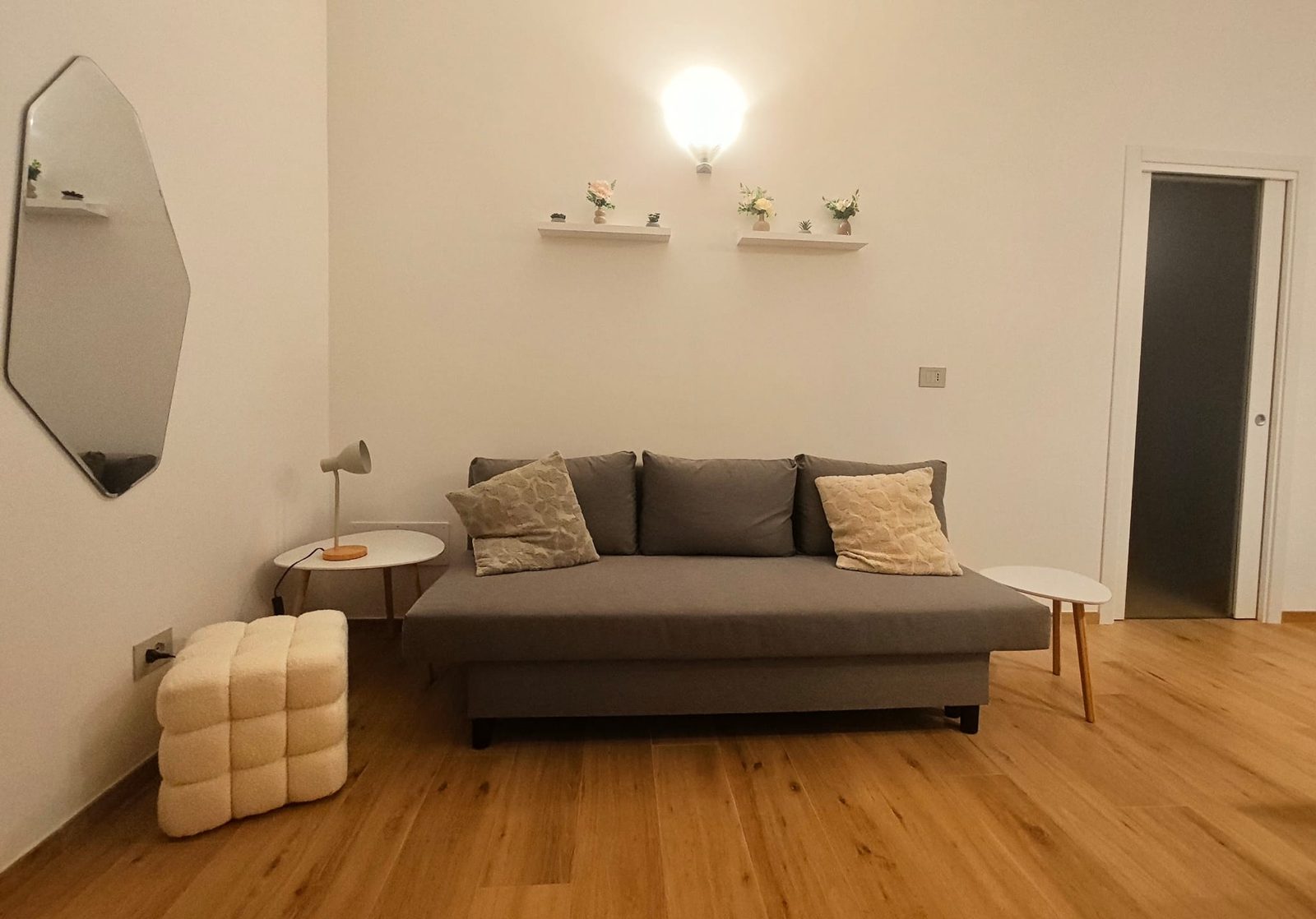 Soggiorno con divano letto grigio e specchio